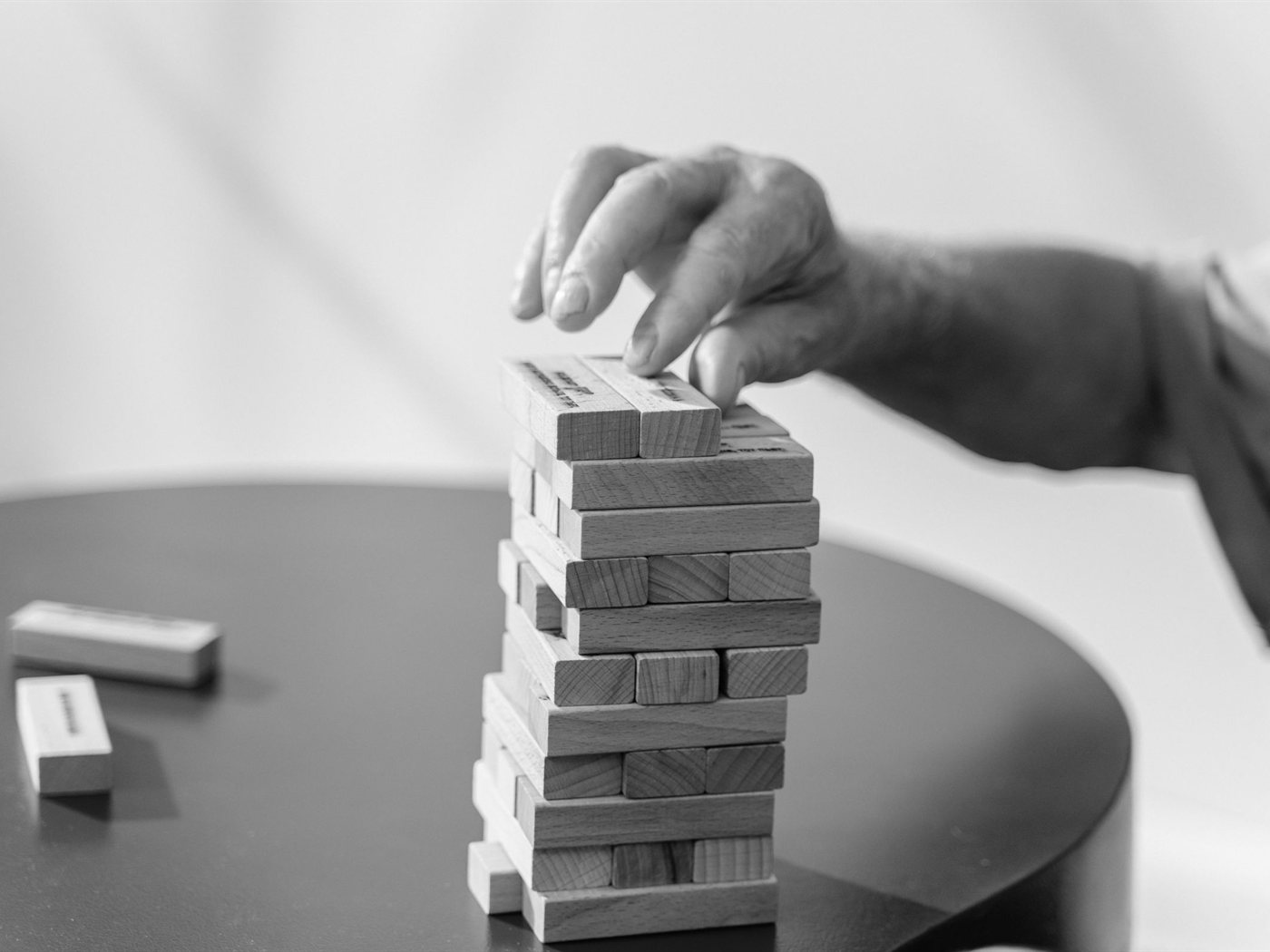 A hand placing a wooden block on top of a stacked block tower